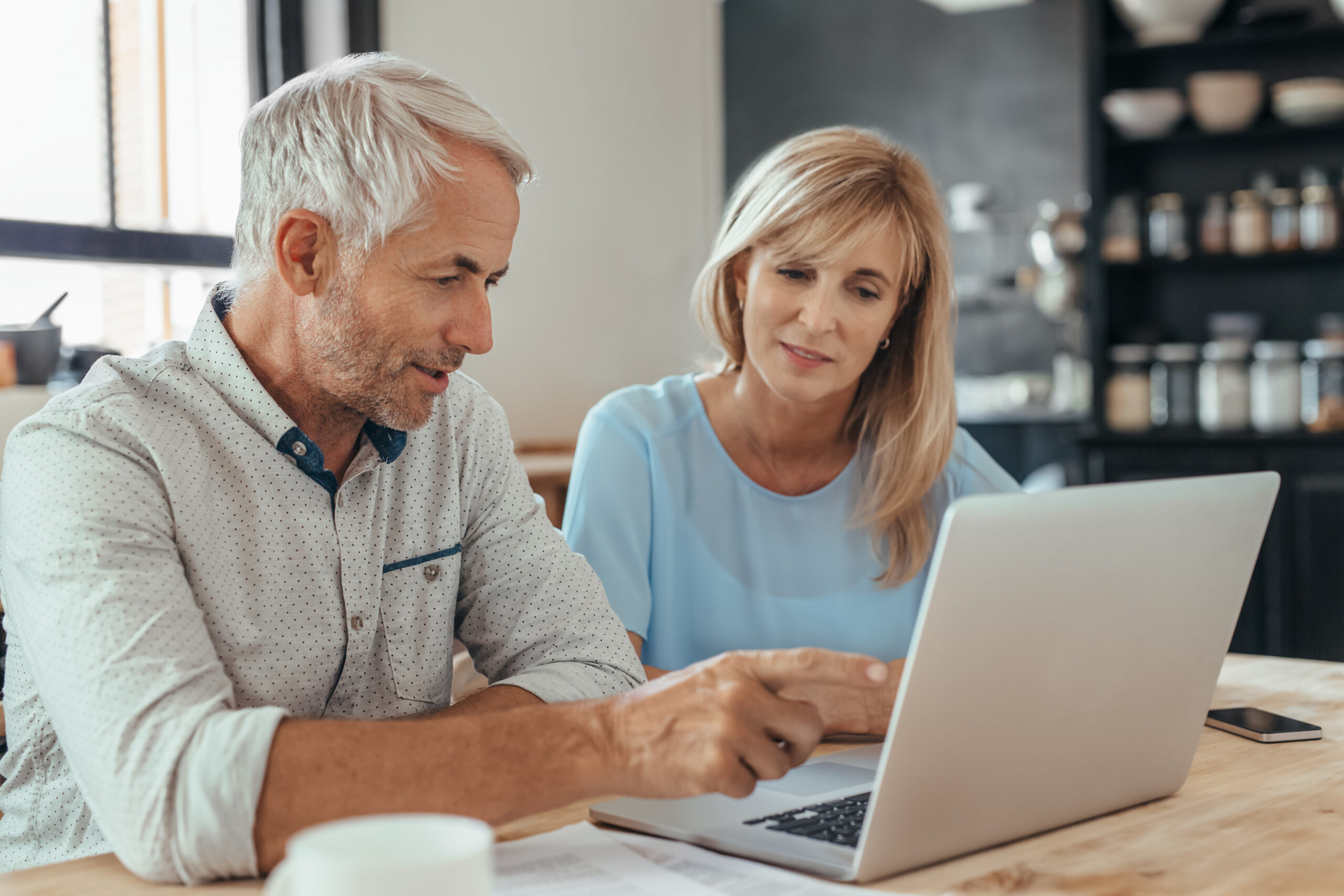 Mature couple sitting together at home doing online banking